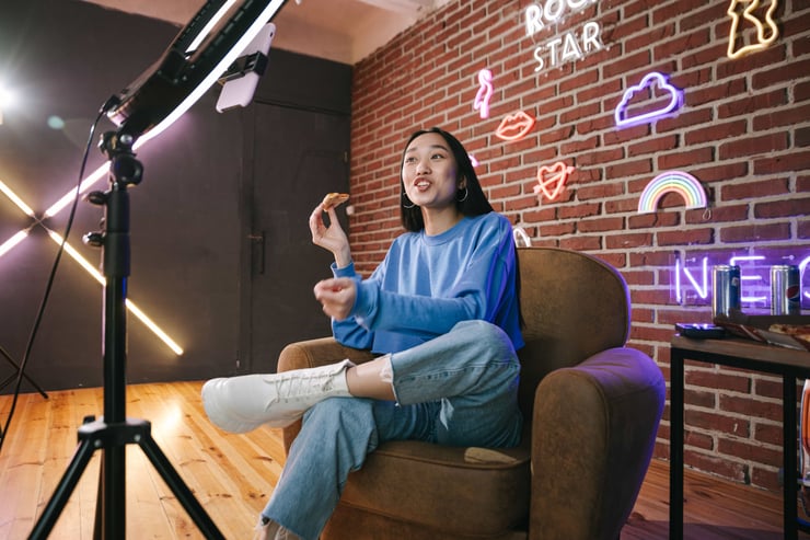 Young Asian woman streaming live indoors with neon lights, engaging audience through technology and creative content