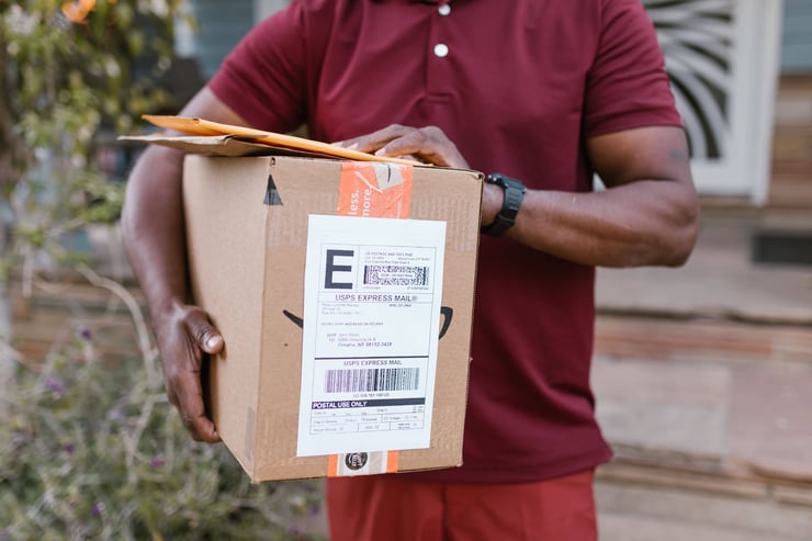 Close-up of a courier delivering a parcel with USPS express mail label outdoors