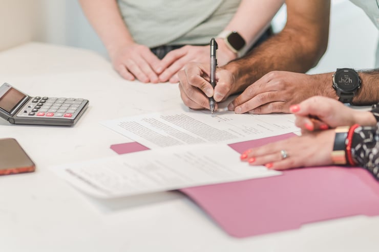 Team collaboration on paperwork with calculator and documents on a white table