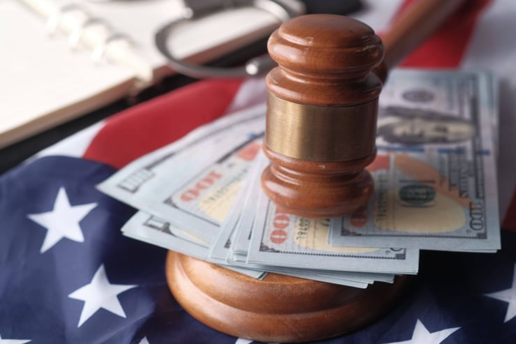Close-up of a judge's gavel resting on US dollar bills and an American flag, symbolizing justice and finance